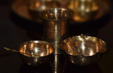 Empty Glass and Bowls of Brass isolated in dark background. Brass is also called as Peetal in Hindi Language.