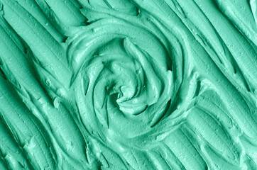 Green cosmetic clay (kelp facial mask, face cream, spirulina body wrap) texture close up, selective focus. Abstract background with circle brush strokes.