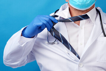 adult male doctor in a white coat tears off his tie, blue background