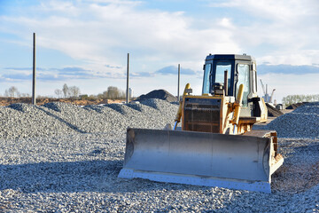 Bulldozer moves gravel during on road work at construction site. Dozer leveling stones for laying...