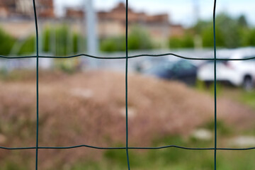 large metal green mesh fence, blurred cityscape