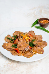 Beef salad with vegetables on a white, round plate