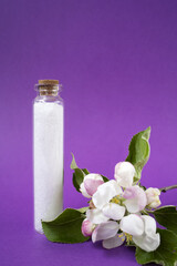 Bathroom salt on the purple background. Apple blossoms. Natural cosmetics. Small business. Copy space. Glass jar