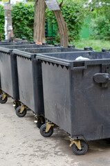 Lined up black plastic trash bins.