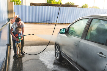 .young mother with her son at a self-service car wash wash their car