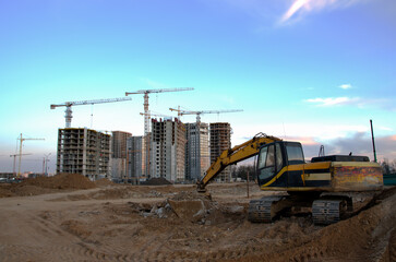 Excavator on earthworks at construction site on sunset background. Backhoe digs ground for the...
