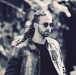Attractive, young blonde bearded male model with combination of braids and dreadlocks posing in the...