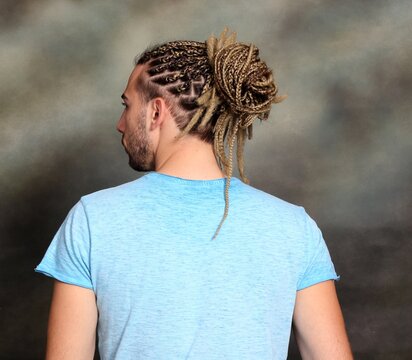 Attractive blonde male model with combination of braids and dreadlocks posing in studio on isolated background. Style, trends, fashion concept.