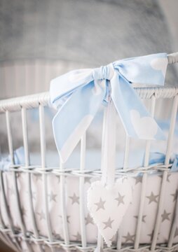 Closeup Vertical Shot Of A White Wooden Baby Basket With A Blue Bow