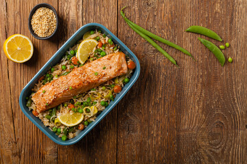 Asian dish. Fried salmon with rice and vegetables. Sprinkled with sesame seeds.