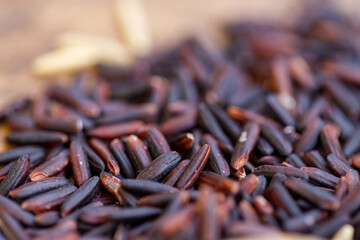 Macro close-up of black wide rice on wooden spoon. Creative food concept.