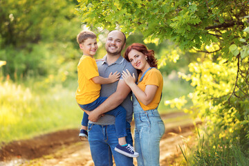 Fototapeta premium A happy family, mom, dad, son are walking, hugging each other outdoors in summer evening.