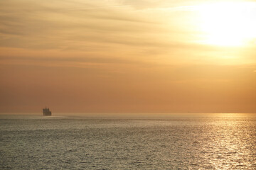 Commercial cargo ship sailing across vast North Sea with golden sunset sky