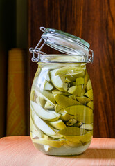 a bunch of fresh salted mango pieces in a glass jar with blurry background