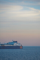 Commercial cargo ship sailing across North Sea in fading dusk light