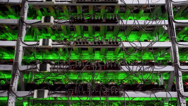 Cryptocurrency mining equipment on large farm. ASIC miners on stand racks mine bitcoin in server room. Blockchain techology application specific integrated circuit. Tripod panorama.