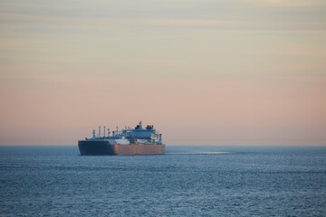 Fototapeta premium Commercial cargo ship sailing alone across North Sea in fading dusk light