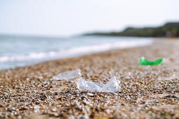 Empty plastic bottle on sea beach. Seashore and water pollution concept. Environmental protection, ecological concept. Waste recycling.