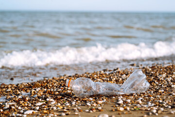 Empty plastic bottle on sea beach. Seashore and water pollution concept. Environmental protection,...