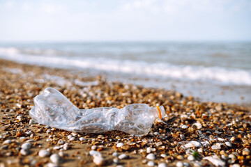 Empty plastic bottle on sea beach. Seashore and water pollution concept. Environmental protection, ecological concept. Waste recycling.