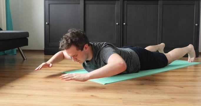 young man doing her workout at home - superman exercise