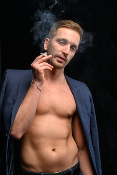 Sports guy in a jacket smokes a cigarette on a black background
