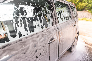 the car is covered with foam at a self-service car wash. Close-up of side windows