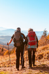 Two old people retired hike through the autumn mountains after quarantine