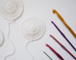 crochet hooks and hand made white wool circles 