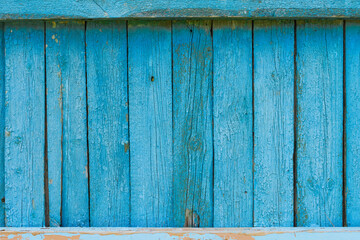 Old fence from the boards. The fence is blue. Cracked paint on the fence.