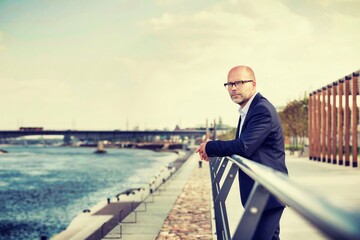 Portrait of thoughtful mature businessman leaning on railing
