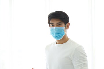 Portrait of a young man wearing a medical mask on white background.