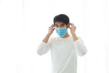 Portrait of young man take off medical mask on white background.