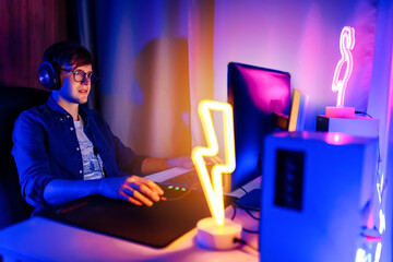 gamer playing video games on a computer with headphones and using a colorful backlit keyboard © Shopping King Louie