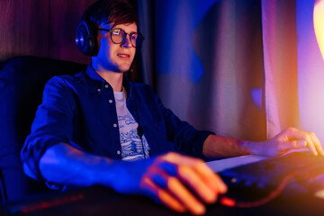 gamer playing video games on a computer with headphones and using a colorful backlit keyboard © Shopping King Louie
