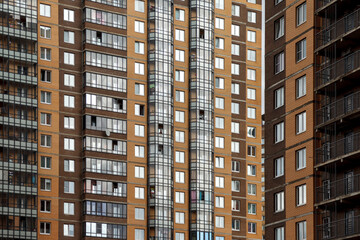 Fototapeta na wymiar Multi-storey residential building. Background new modern house. Detailed photo of multi-storey residential with large number of Windows. Dormitories for low-income residents of Russia. Architecture