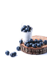 Freshly picked juicy blueberries on a wooden board in a white bucket. Blueberry antioxidant. Healthy eating concept. White background.