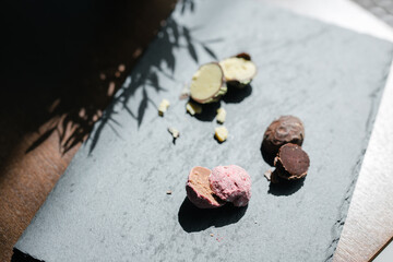 three cut up truffle candies on a black plate with green and pink filling