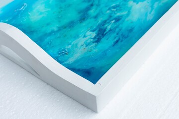Closeup shot of a white tray with epoxy resin art with blue alcohol inks
