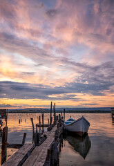 Fototapeta premium mood and tranquility at a lake coast with a boat at a wooden pier. Vertical view