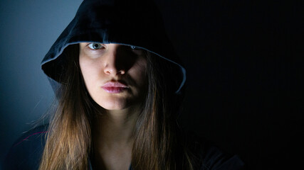 Portrait of a woman with a hood in the dark.