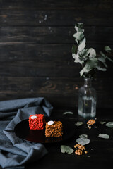 two red and chocolate cupcakes on a black plate against the background of a vase