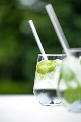 Beautiful glass of water or mojito with lime and mint cocktail on the gree background and white table summer vibe and atmosphere