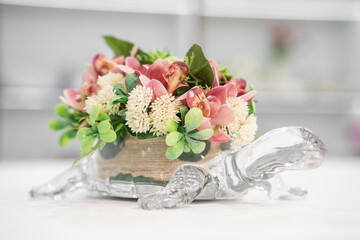Сrystal vase in the form of a turtle on a table with a bouquet of flowers