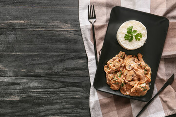 Plate with tasty beef stroganoff and rice on table