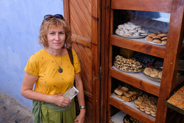 Pretty smiling woman standing near sweet cakes sale in the blue city of Chefchaouen, Morocco.
