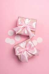 Two gifts or present boxes decorated with confetti on pink pastel background. Top view. Flat lay composition for birthday or wedding. Vertical orientation. 