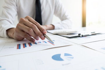 Businessman is analyzing marketing strategy from the selling performance graph in the office room.