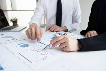 Two business people are discussing and analyze marketing strategy from the sell performance graph in the office room.