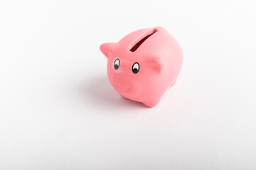 Side view of small pink piggy bank isolated on a white table, concept of saving for financial crisis or unemployment
